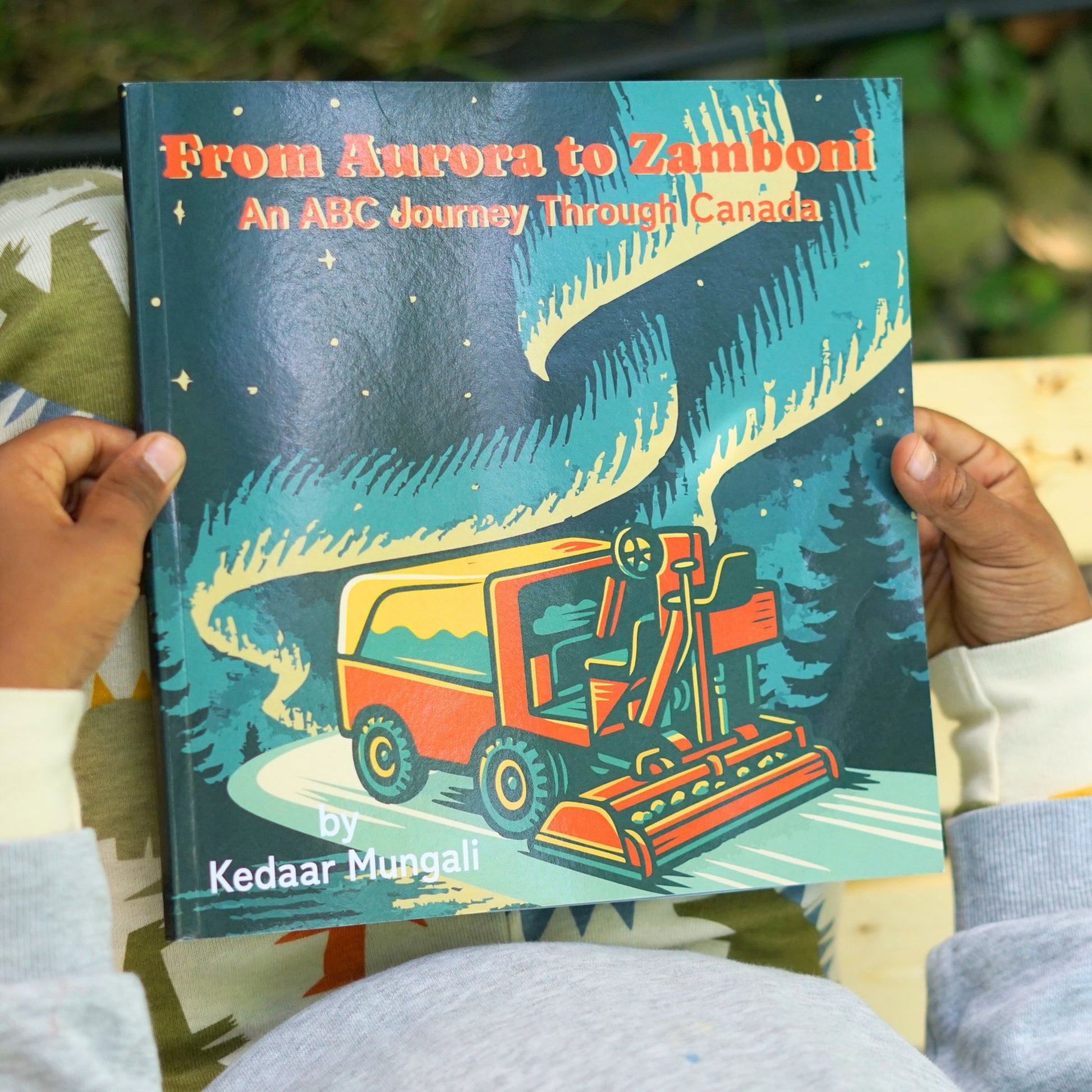 A child reading the Children's book From Aurora to Zamboni by Kedaar Mungali front cover page